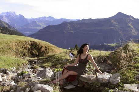 Frau sitzt auf einem Stein und lacht